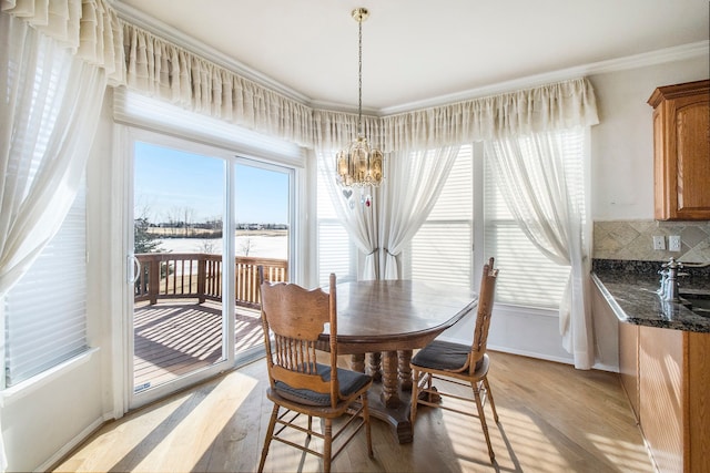 dining space featuring light wood-style floors, an inviting chandelier, and crown molding