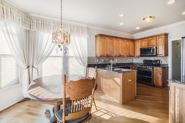 kitchen with brown cabinetry, range with two ovens, a healthy amount of sunlight, and a chandelier