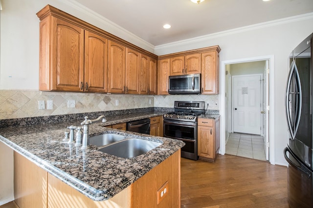 kitchen featuring ornamental molding, a peninsula, stainless steel appliances, and a sink