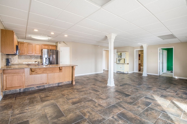 kitchen featuring a sink, open floor plan, appliances with stainless steel finishes, a peninsula, and ornate columns