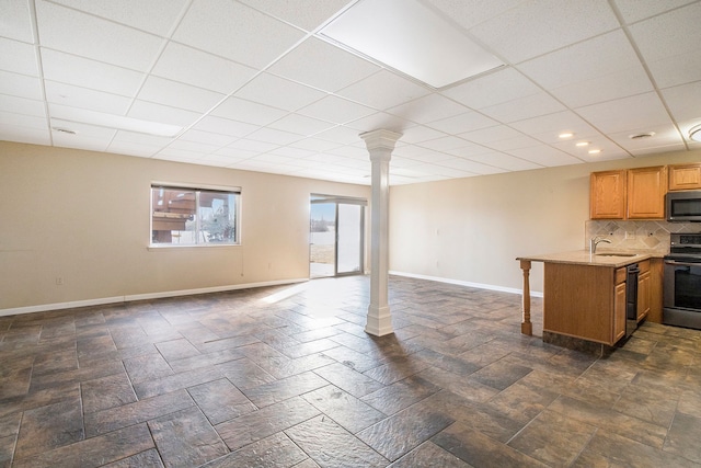 interior space featuring stone finish floor, a paneled ceiling, baseboards, and a sink