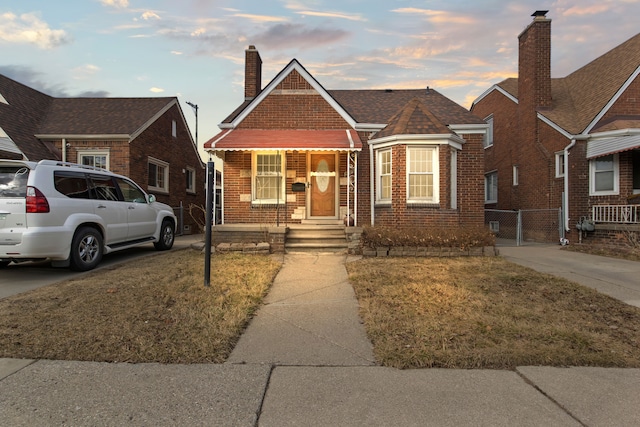 bungalow featuring brick siding, fence, concrete driveway, a chimney, and a gate