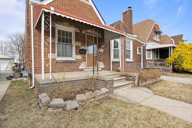 view of front of property featuring brick siding, roof with shingles, and a chimney