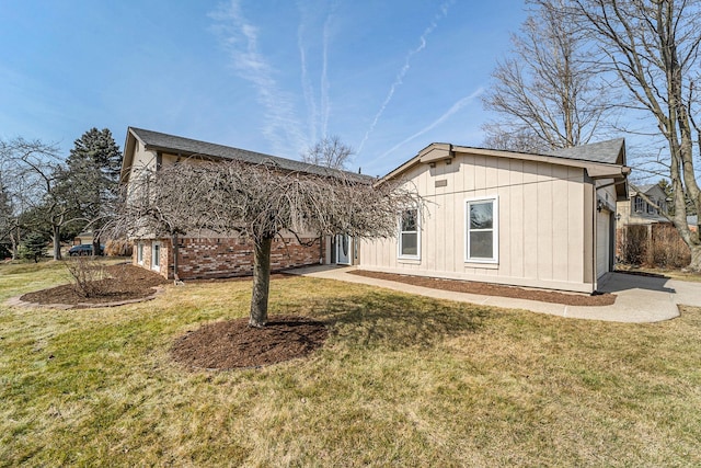 rear view of property featuring a lawn and brick siding