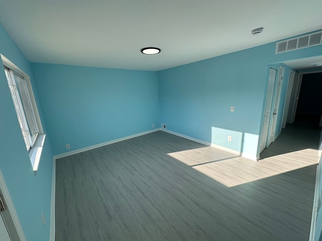 empty room with visible vents, baseboards, and wood finished floors