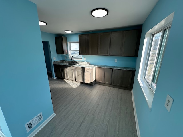 kitchen featuring a sink, visible vents, baseboards, and light wood-style flooring