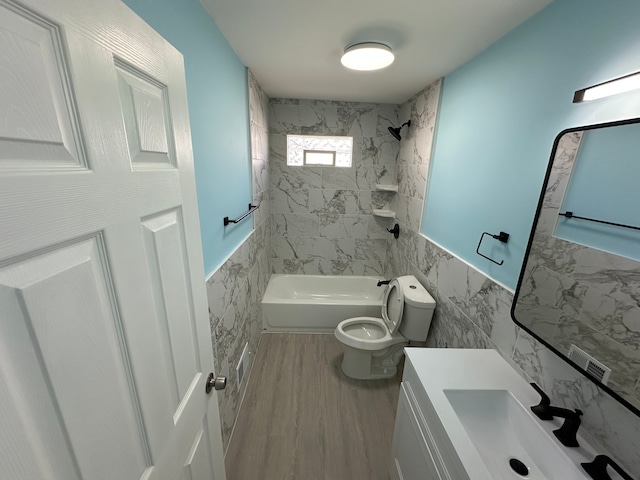 full bath with toilet, wainscoting, wood finished floors, tile walls, and  shower combination