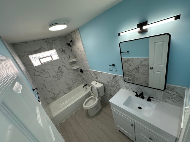 bathroom with a wainscoted wall, toilet, shower / washtub combination, tile walls, and vanity