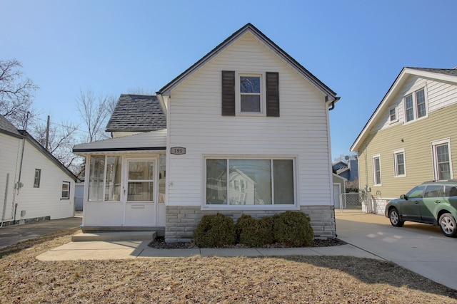 traditional-style house featuring concrete driveway, stone siding, and roof with shingles