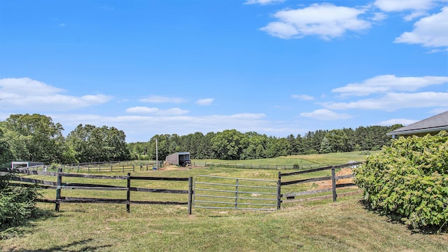 view of yard with an outbuilding, a rural view, fence, and a forest view