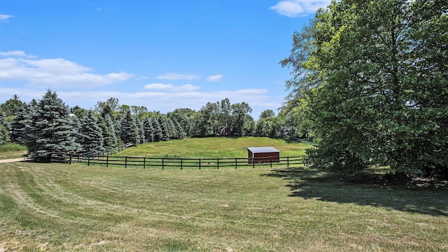 view of yard featuring an outbuilding, a rural view, and fence