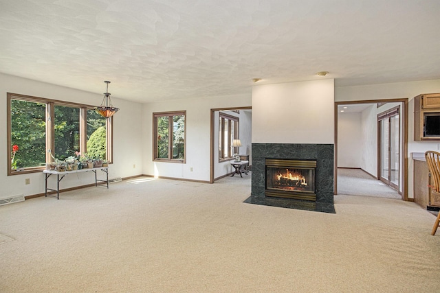 unfurnished living room featuring baseboards, visible vents, a high end fireplace, and light carpet