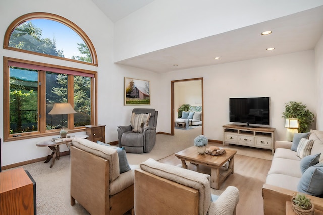 living room with recessed lighting, baseboards, light colored carpet, and a towering ceiling