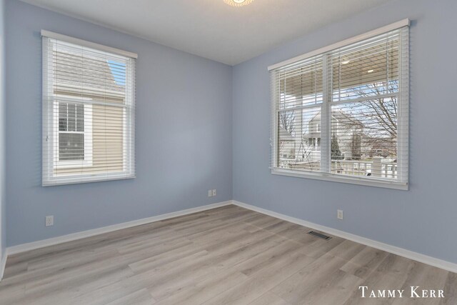 empty room with visible vents, baseboards, and wood finished floors