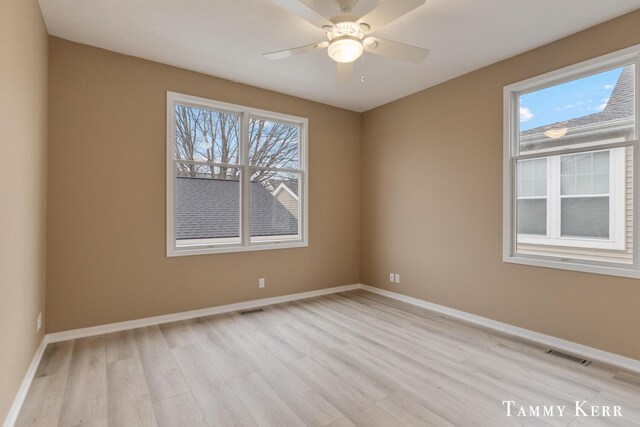 spare room with light wood finished floors, visible vents, a ceiling fan, and baseboards