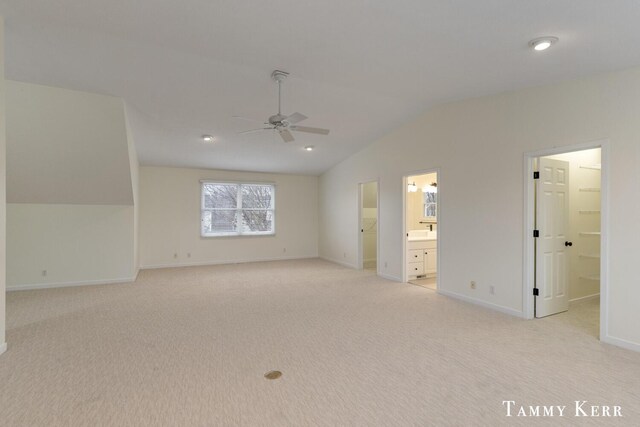 unfurnished bedroom with baseboards, lofted ceiling, ceiling fan, ensuite bathroom, and light colored carpet