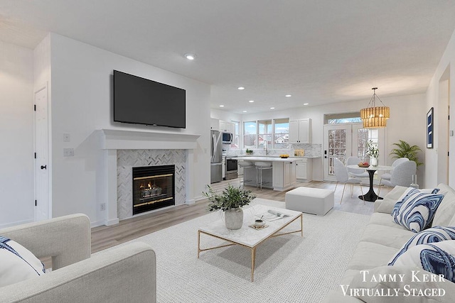 living room with recessed lighting, a fireplace, and light wood finished floors