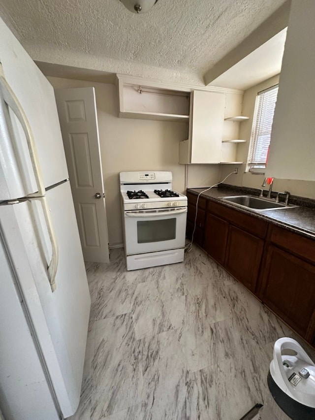 kitchen featuring white appliances, dark countertops, open shelves, and a sink