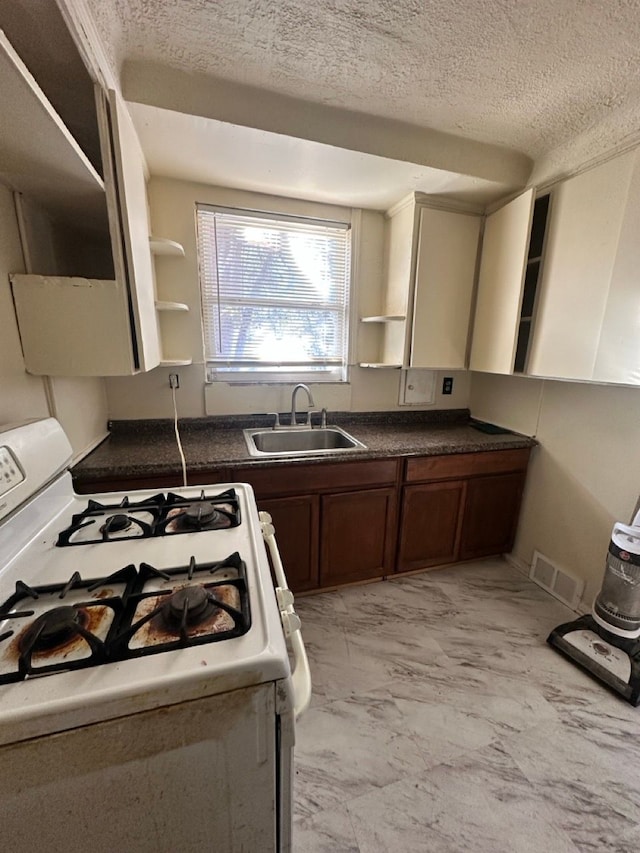 kitchen featuring dark countertops, open shelves, gas range gas stove, marble finish floor, and a sink