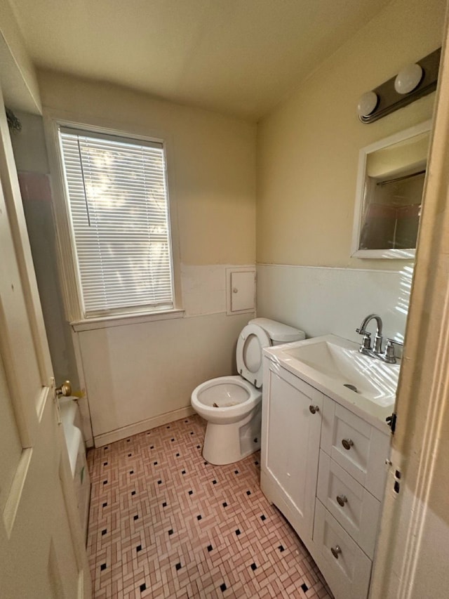 bathroom with vanity, toilet, and wainscoting