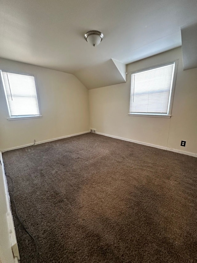 bonus room with dark colored carpet, baseboards, a healthy amount of sunlight, and vaulted ceiling