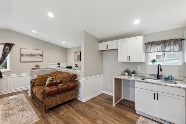 kitchen with lofted ceiling, white cabinets, a wealth of natural light, and a sink