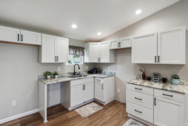 kitchen featuring dark wood finished floors, lofted ceiling, recessed lighting, a sink, and white cabinets