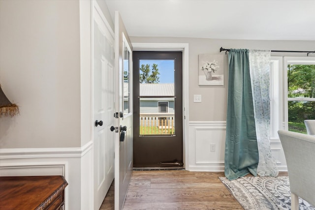 doorway to outside featuring a wainscoted wall and wood finished floors