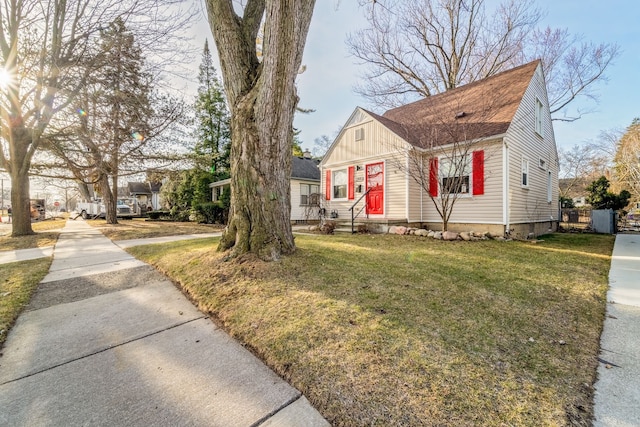 bungalow-style home with board and batten siding, a shingled roof, a front yard, and entry steps