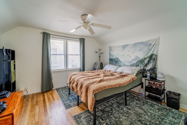 bedroom with lofted ceiling, wood finished floors, baseboards, and ceiling fan