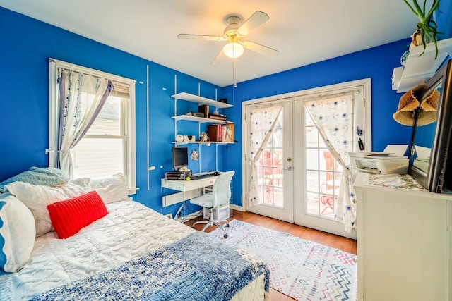 bedroom with french doors, multiple windows, wood finished floors, and access to outside