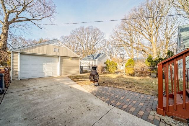 view of yard featuring a garage, an outdoor structure, driveway, and fence