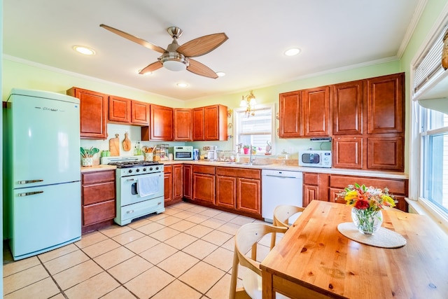 kitchen with light countertops, ornamental molding, light tile patterned floors, white appliances, and a sink