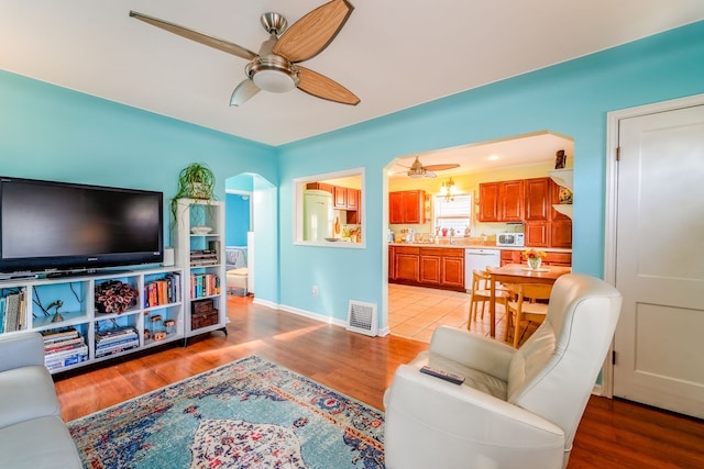 living room featuring baseboards, light wood-style floors, visible vents, and ceiling fan