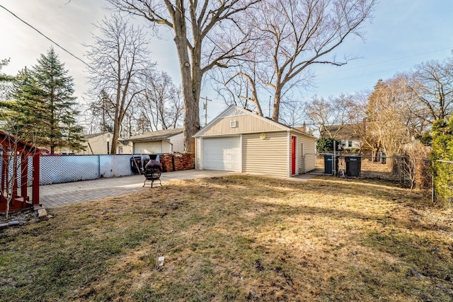 view of yard featuring a garage, an outbuilding, and fence