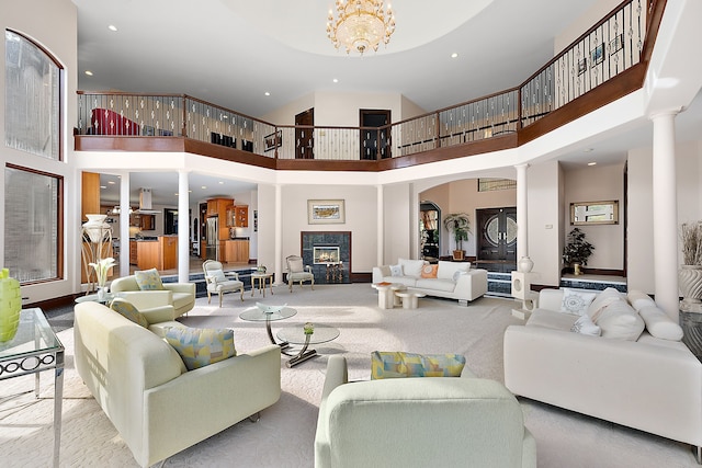 living room featuring a notable chandelier, decorative columns, recessed lighting, and a lit fireplace