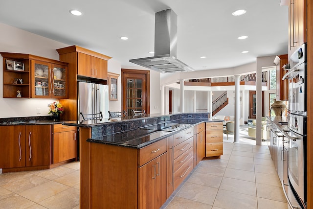 kitchen featuring island range hood, open shelves, glass insert cabinets, appliances with stainless steel finishes, and a center island