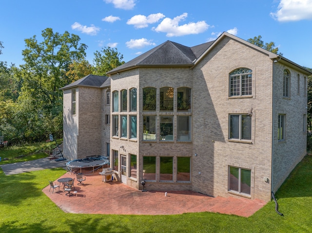 rear view of house featuring brick siding, a lawn, and a patio area