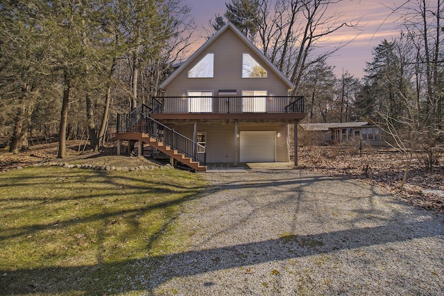 chalet / cabin featuring a wooden deck, a lawn, gravel driveway, and stairs