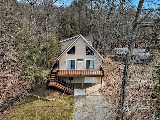 chalet / cabin featuring stairway, an attached garage, and driveway