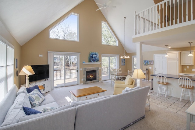 living room featuring light colored carpet, light tile patterned flooring, a fireplace, and ceiling fan with notable chandelier