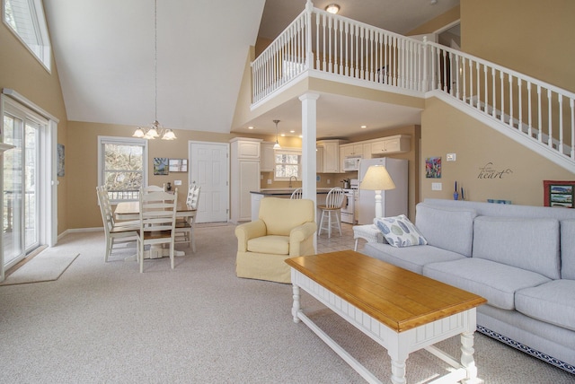 living room with a wealth of natural light, light carpet, a notable chandelier, and a towering ceiling