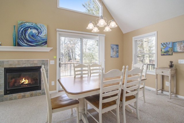 carpeted dining room featuring a healthy amount of sunlight, a tile fireplace, an inviting chandelier, and baseboards