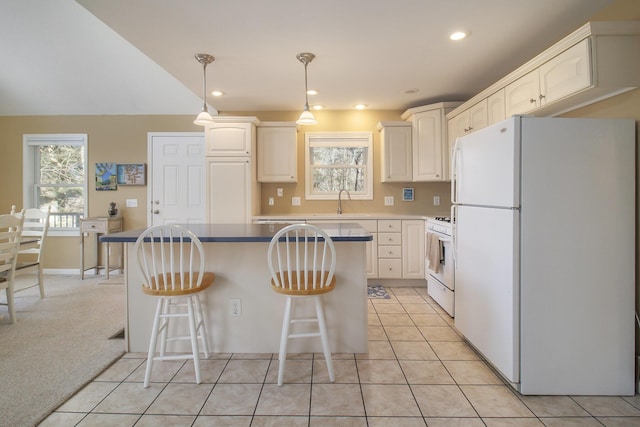 kitchen featuring light tile patterned floors, white appliances, a kitchen island, and a sink