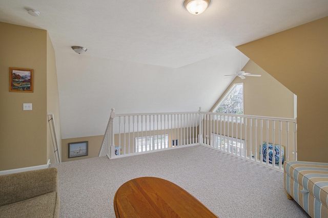 interior space with a ceiling fan, carpet flooring, and vaulted ceiling