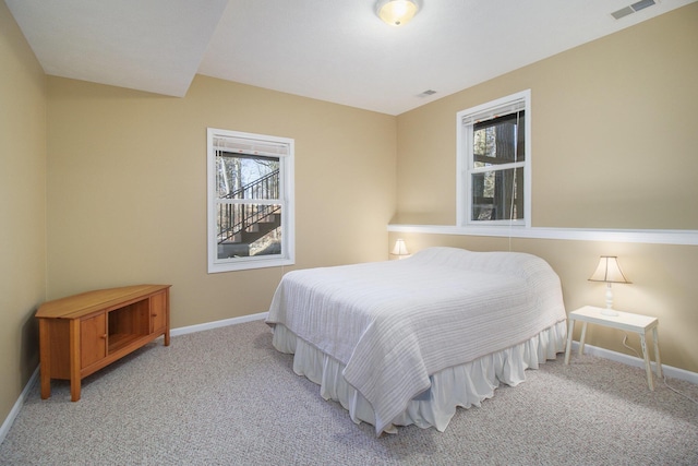 bedroom with multiple windows, visible vents, and light carpet