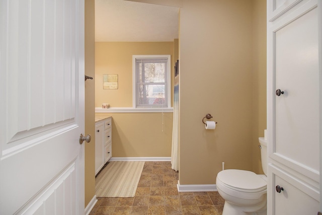 bathroom with baseboards, toilet, and vanity