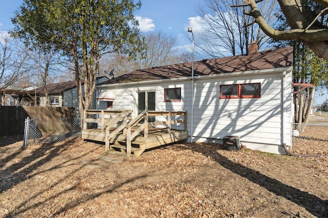 rear view of house with a chimney, a deck, and fence