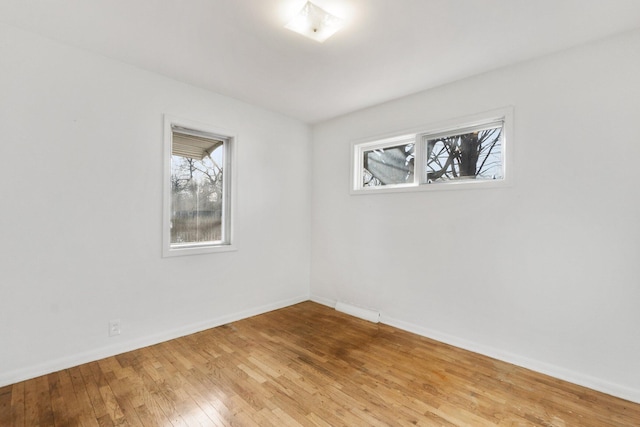 unfurnished room featuring a wealth of natural light, light wood-type flooring, and baseboards