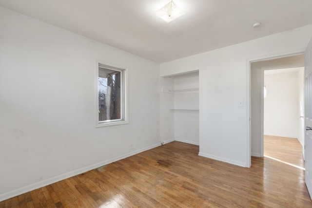 unfurnished bedroom featuring a closet, baseboards, and wood finished floors